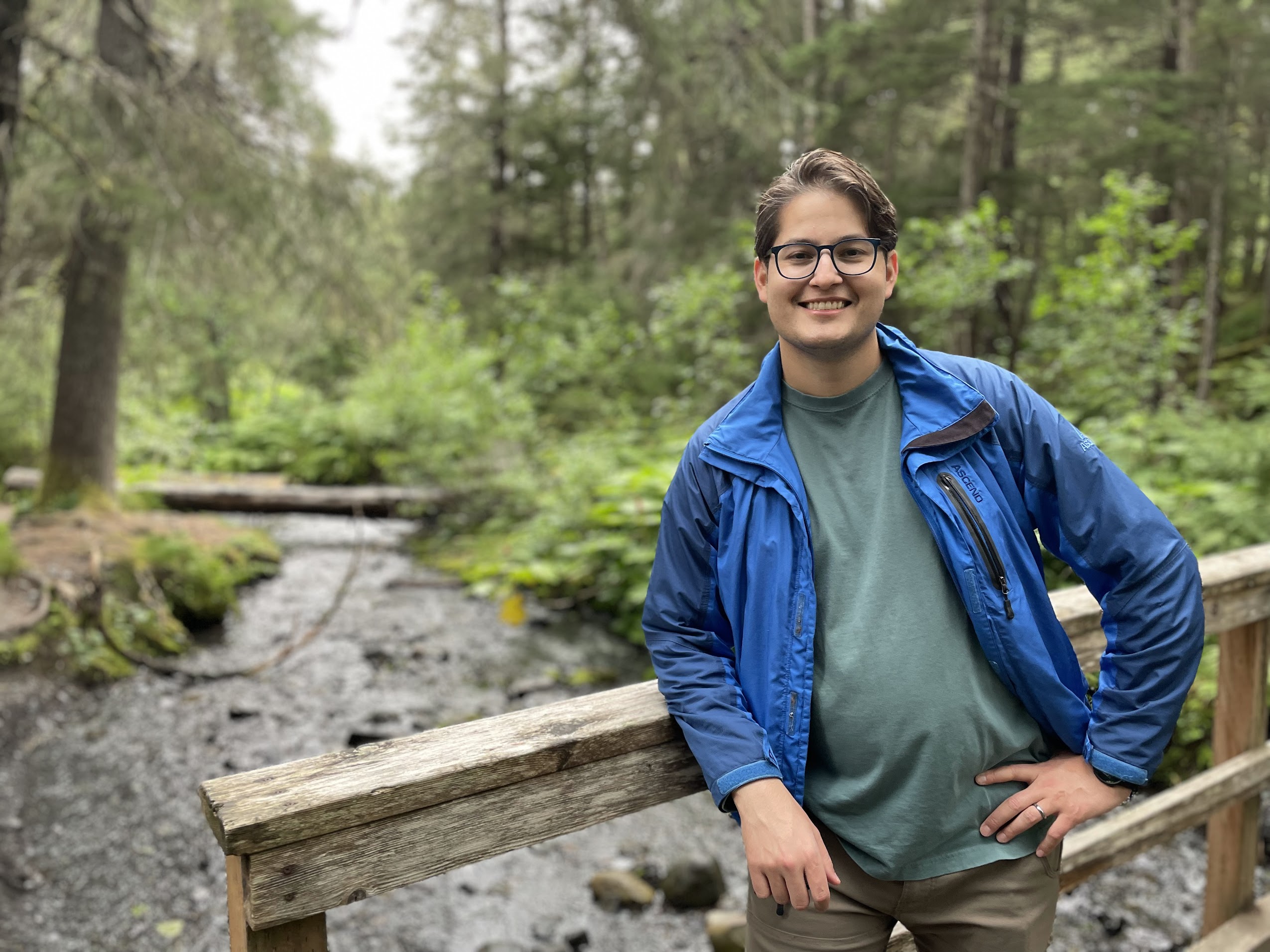 Alex Cantu smiling on a wooden footbridge over a creek